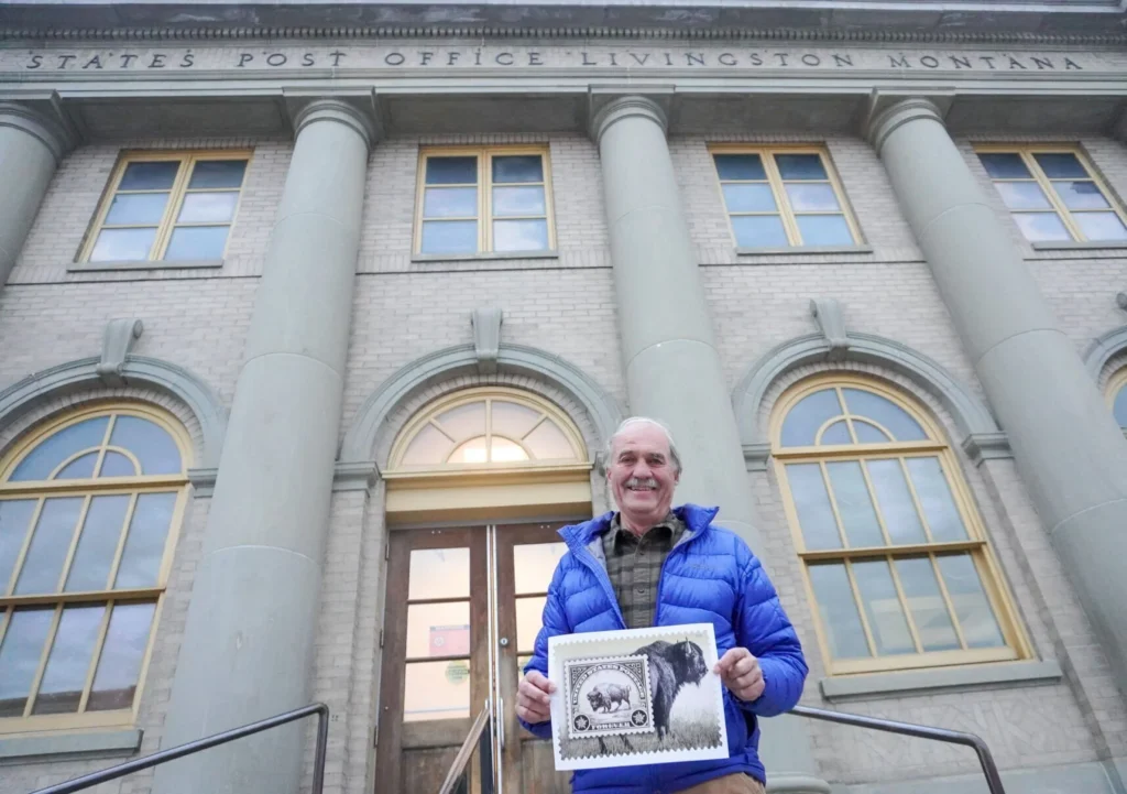 Livingston photographer Tom Murphy holds an enlarged print of a 2026 Forever Stamp featuring one of his bison photos in front of the Livingston Post Office on Monday, Nov. 3.